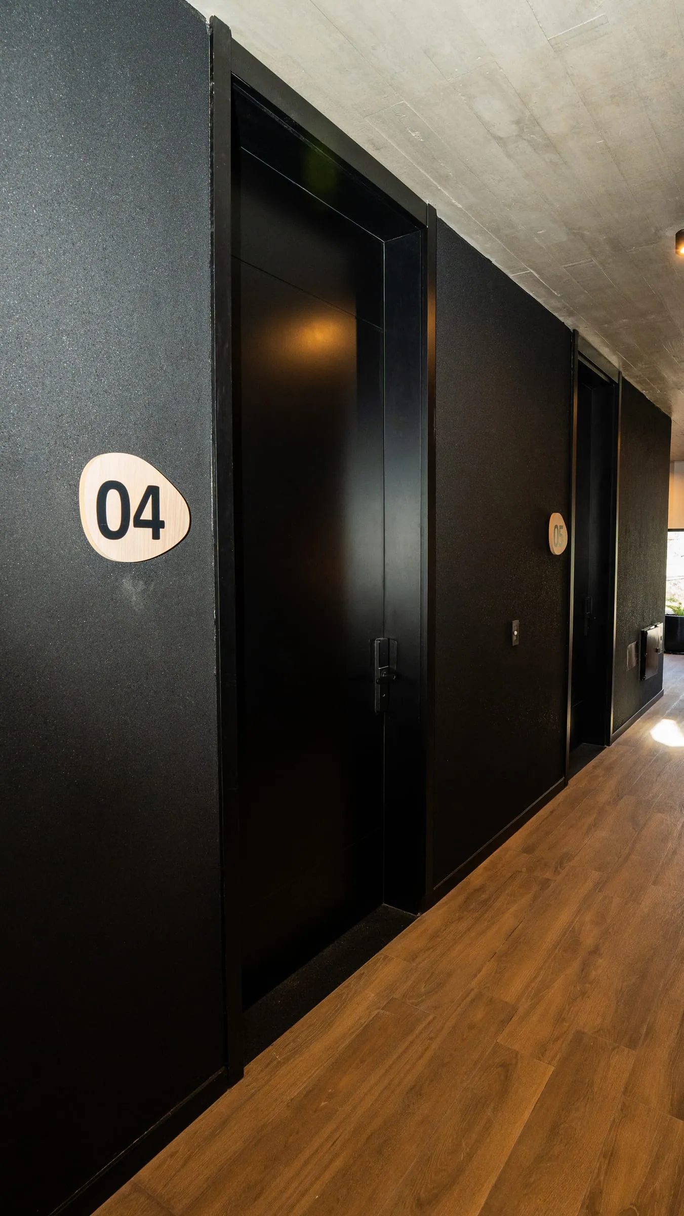 Pasillo con puertas de ingreso negras numeradas de oficinas en Buena Vista Aldea Black