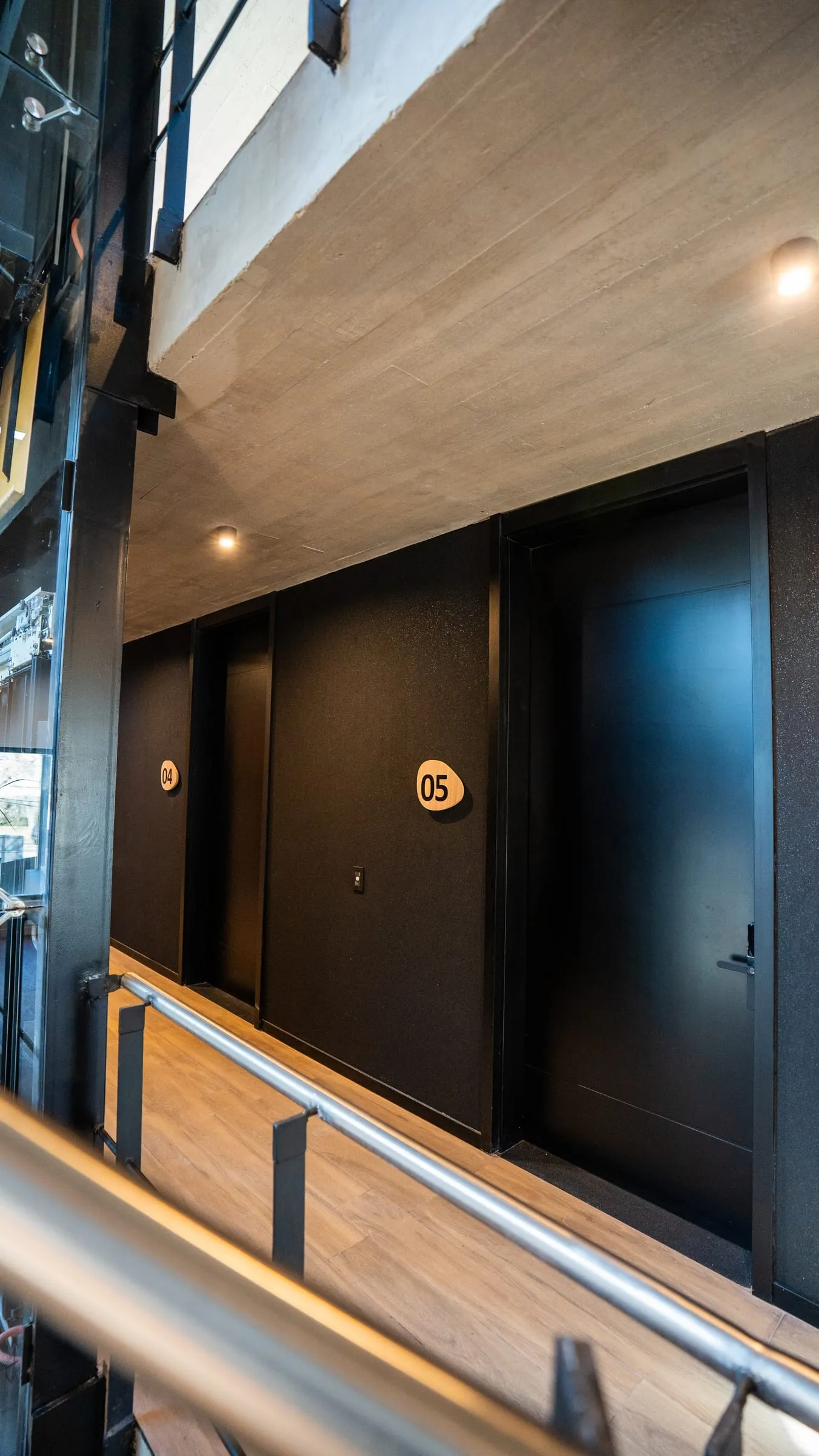 Circulación con puertas negras de oficinas y revestimiento de madera en Buena Vista Aldea Black