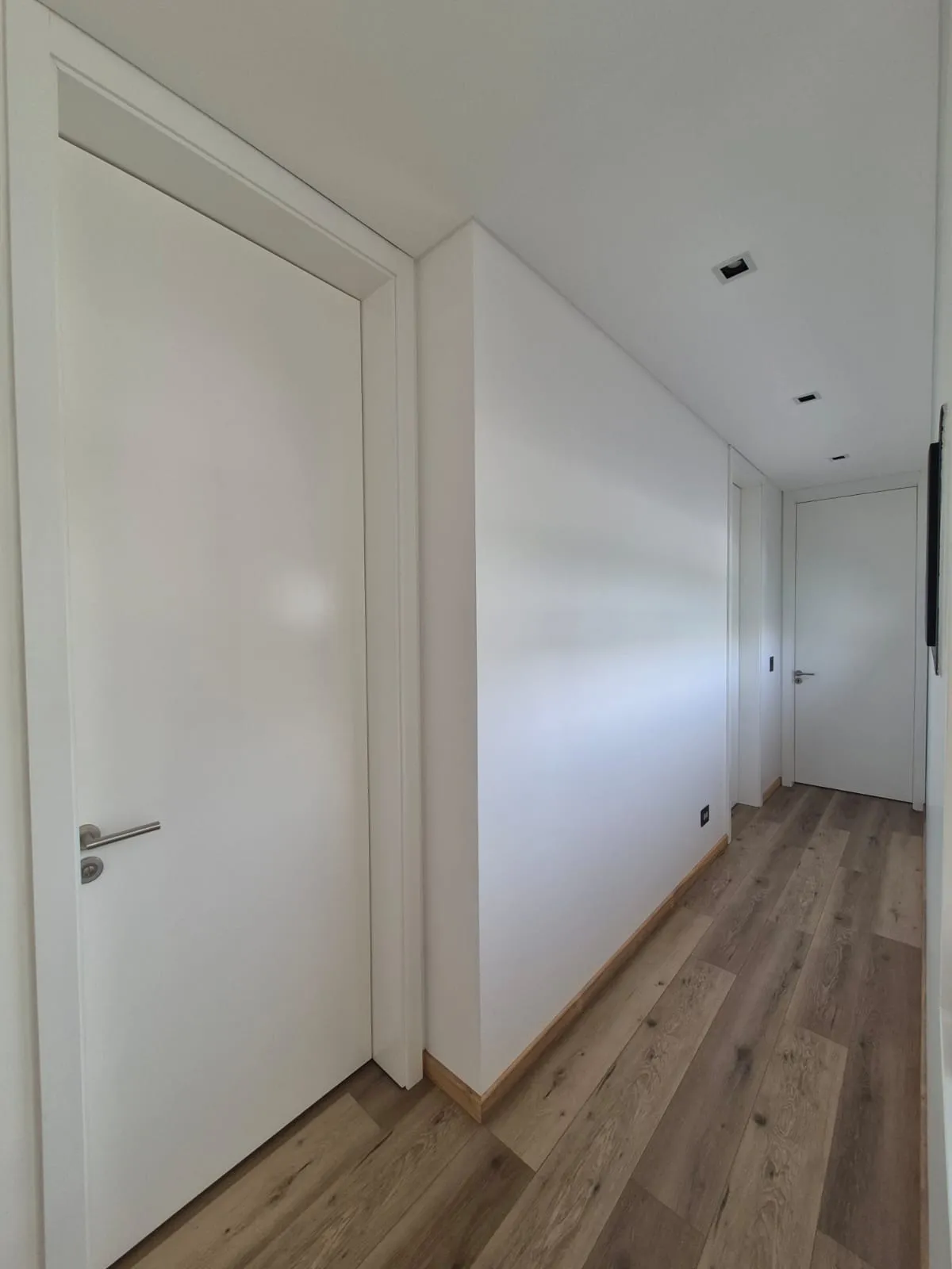 Pasillo con puertas placa laqueadas blancas a medida en perspectiva, Casa Vida
