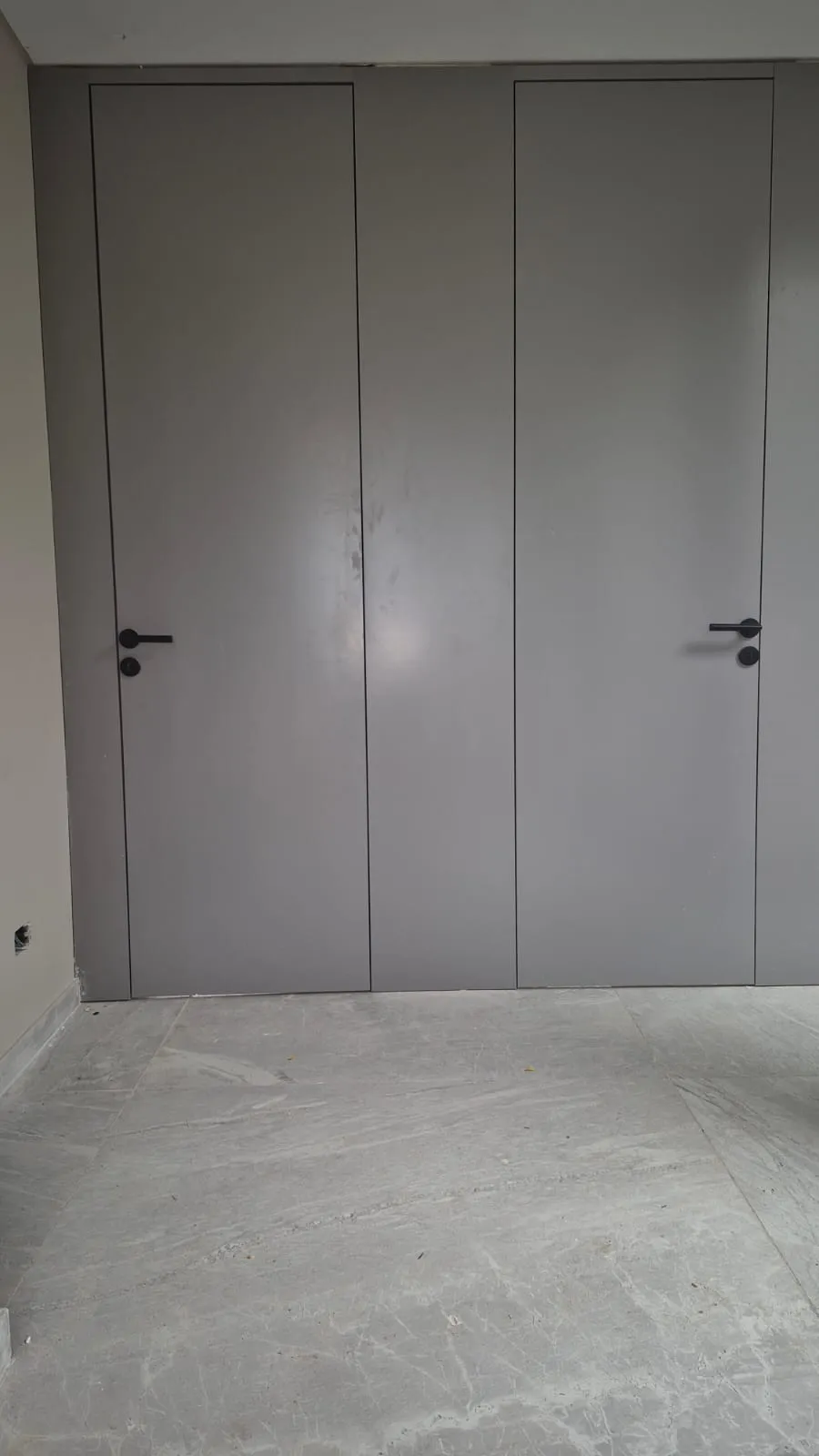Puerta filomuro gris integrada a la pared con terminación al ras