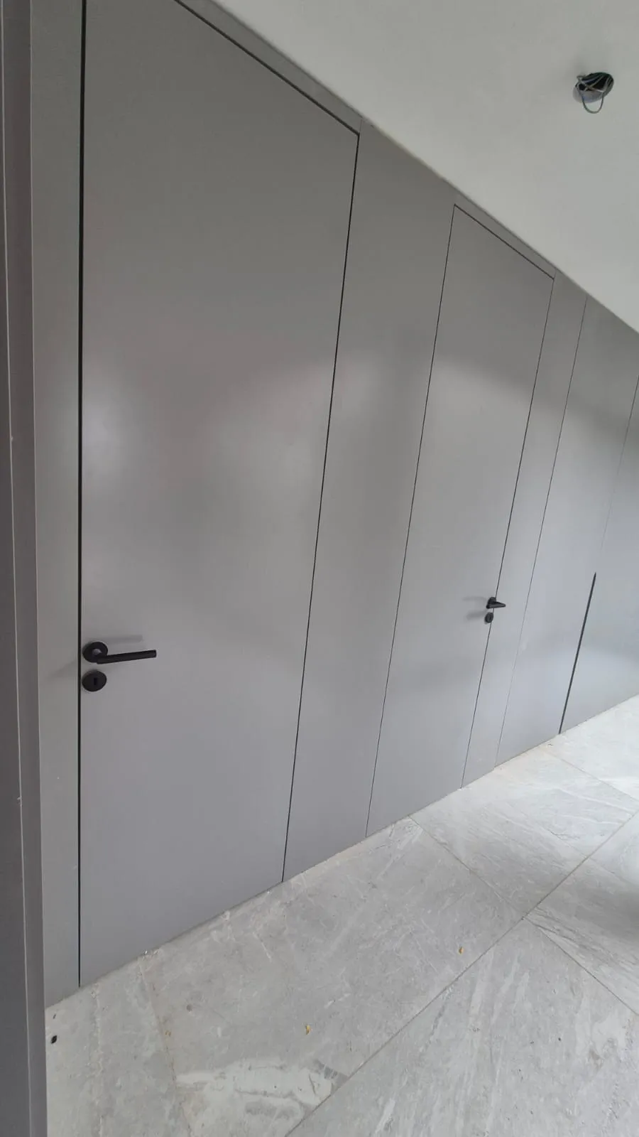 Puerta filomuro gris integrada a la pared con terminación al ras