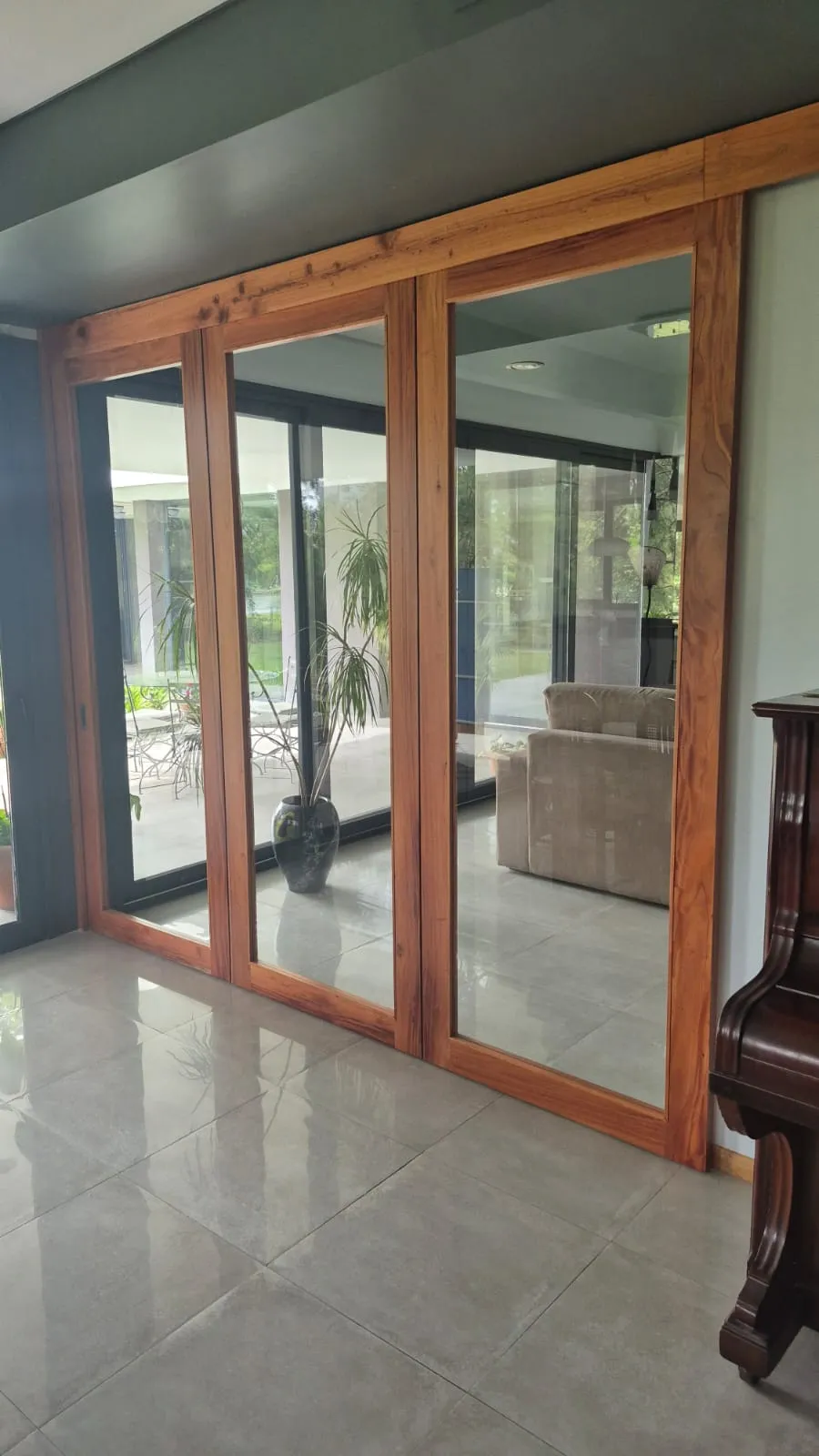 Puertas corredizas de madera con paños de vidrio dividiendo living y galería