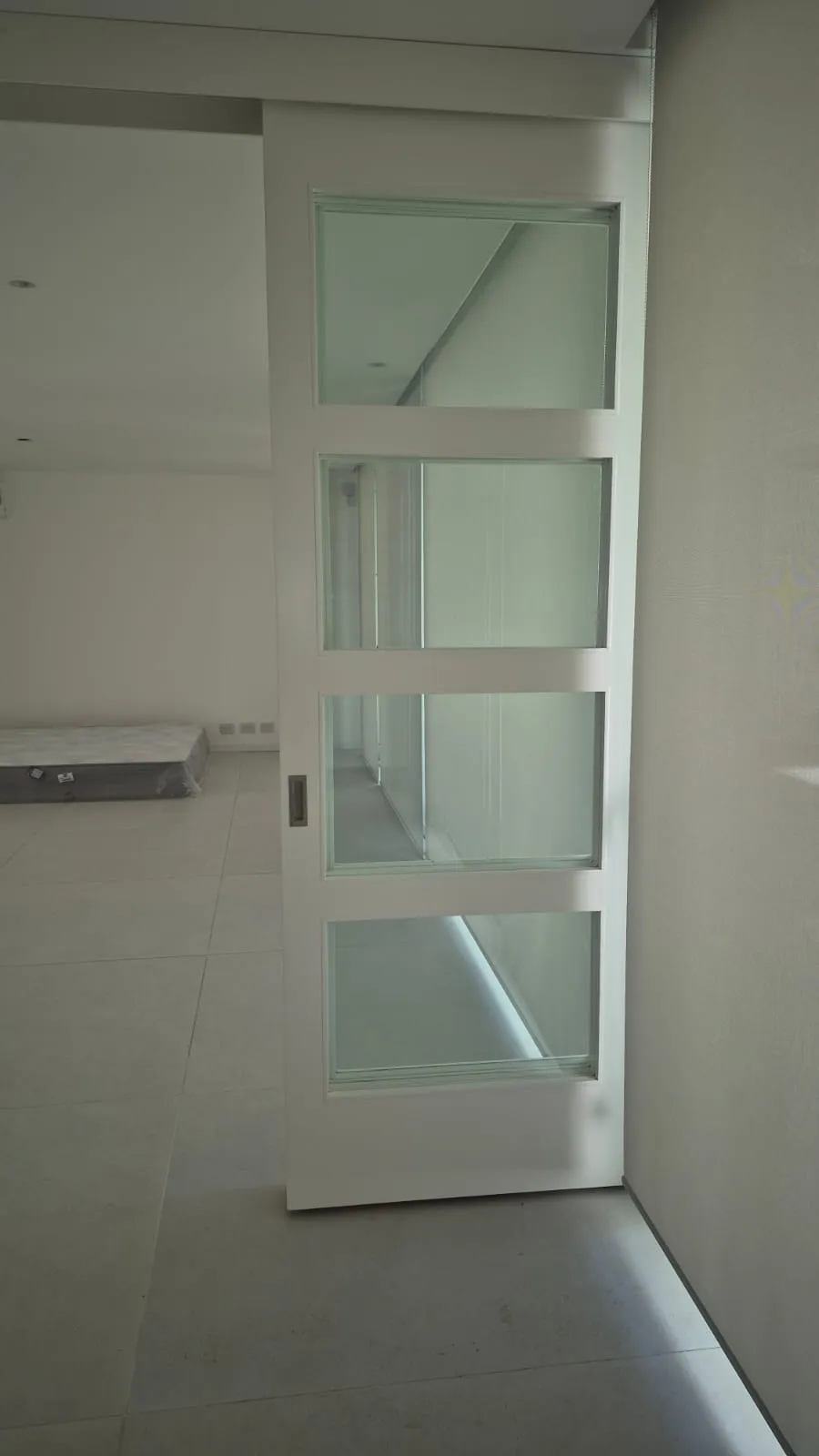 Divisor corredizo de ambientes en laca blanca con paños de vidrio a medida