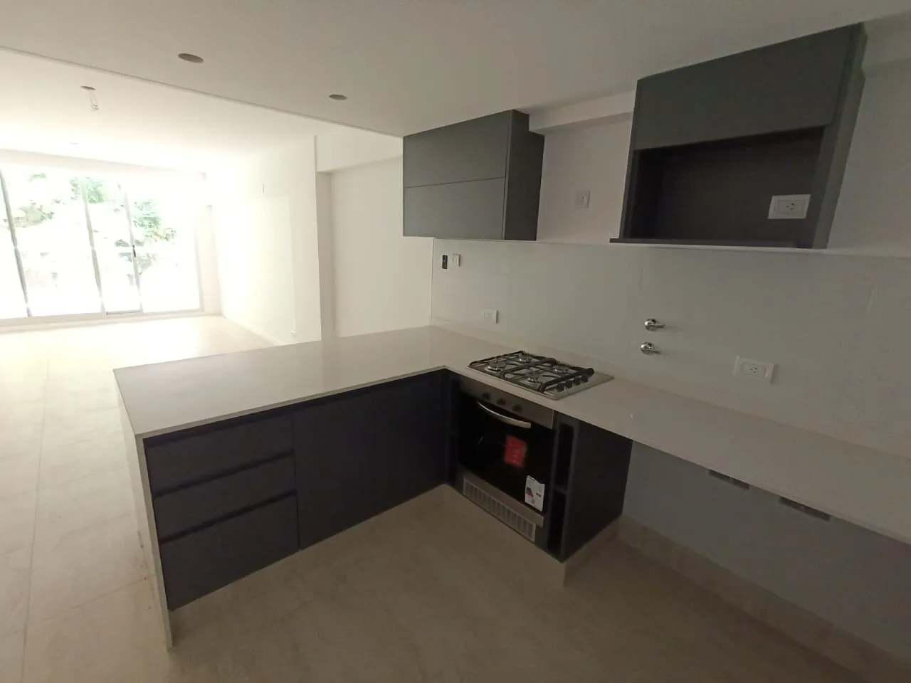 Cocina en melamina gris con península y horno empotrado en unidad de Sol Patagonia