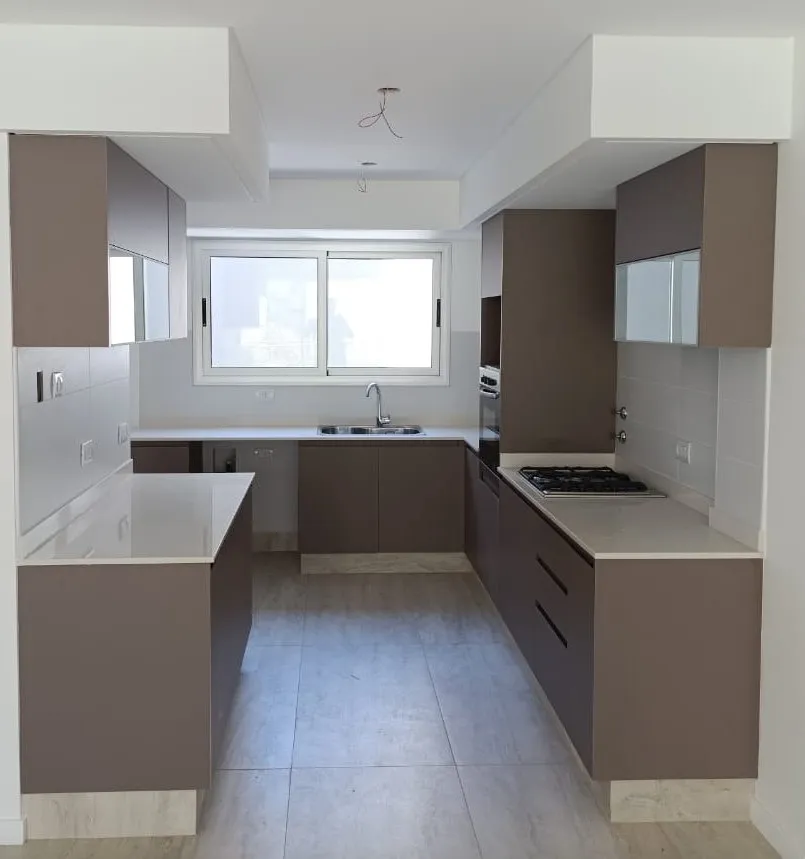 Cocina en melamina con península junto a ventana en unidad de Sol Patagonia